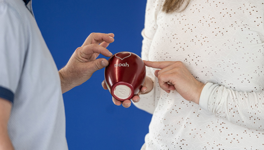 Die Frau hält eine rote Tierurne